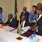 Officials from ministries of the governments of Malawi and Mozambique sign agreements as their respective ministers (back) look on--Photo by Watipaso Mzungu