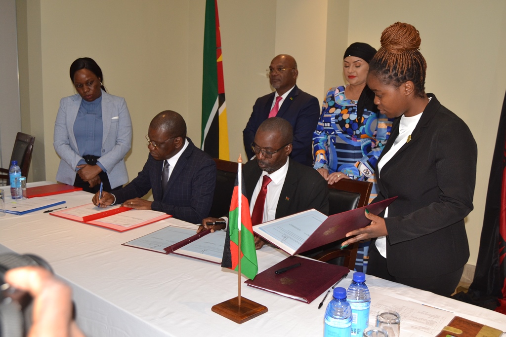 Officials from ministries of the governments of Malawi and Mozambique sign agreements as their respective ministers (back) look on--Photo by Watipaso Mzungu