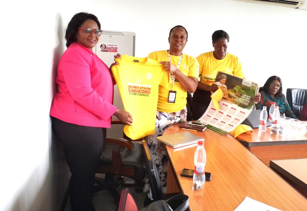 Women in Business urged to embrace digital financing system 2 Kangaude presenting a t shirt to Mwenelupembe