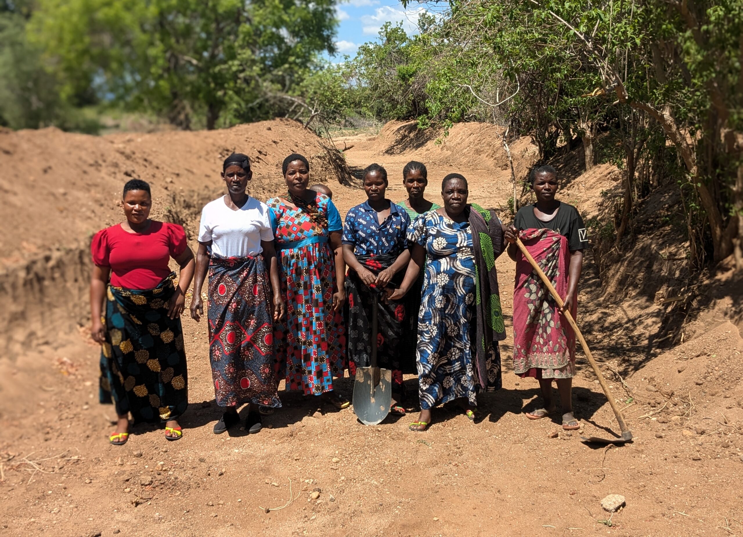The women pose at channel they are digging scaled