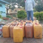 Kayola standing behind his fuel Jerry cans Karonga-Chiweta