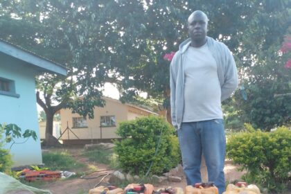 Kayola standing behind his fuel Jerry cans